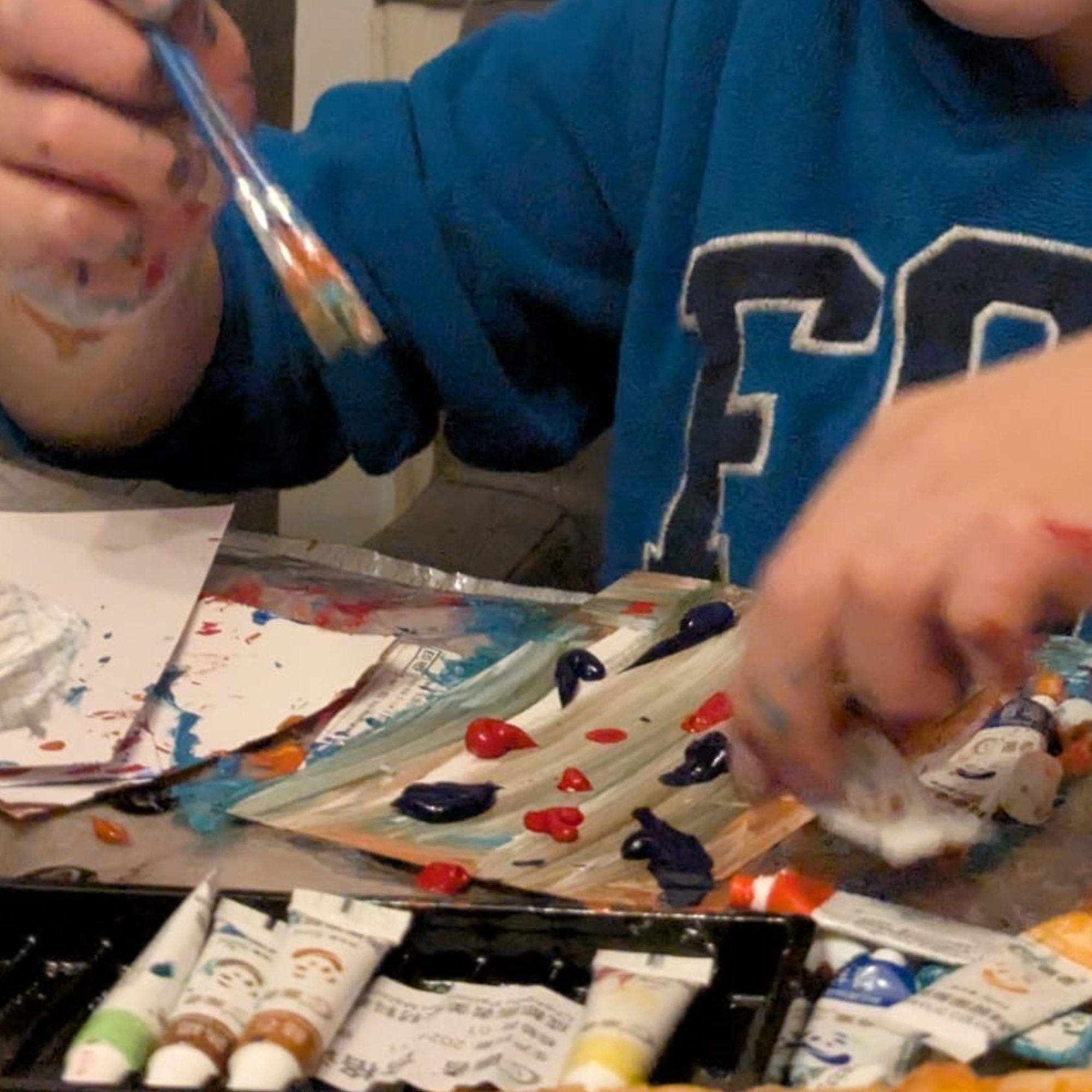 Hands using paint during a creative learning activity.